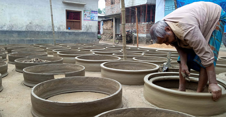 বাড়ির উঠোনে মাটি দিয়ে সামগ্রী বানাচ্ছেন এক মৃৎশিল্পী
