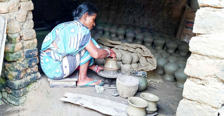 মাটি দিয়ে সামগ্রী বানাচ্ছেন এক নারী মৃৎশিল্পী